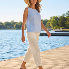 Woman wearing Clementine lightweight trousers in cream on a sunny waterfront boardwalk