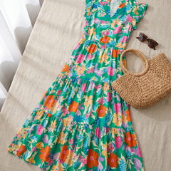 Lila floral tiered midi dress green flat-lay styled with straw bag and sunglasses