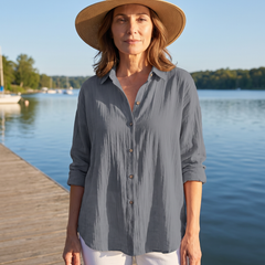 Woman wearing the Abigail grey pleated blouse on a lakeside boardwalk
