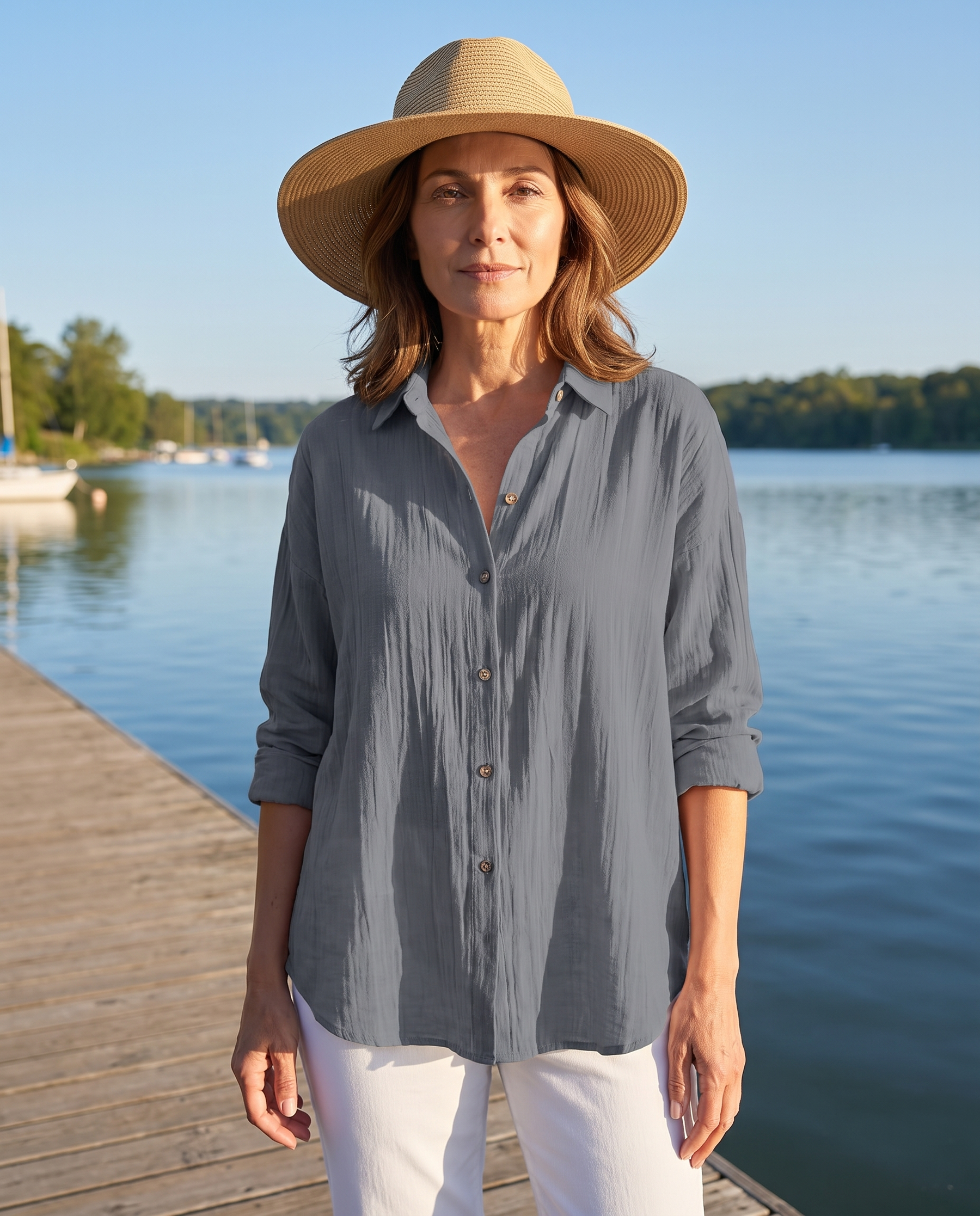 Woman wearing the Abigail grey pleated blouse on a lakeside boardwalk