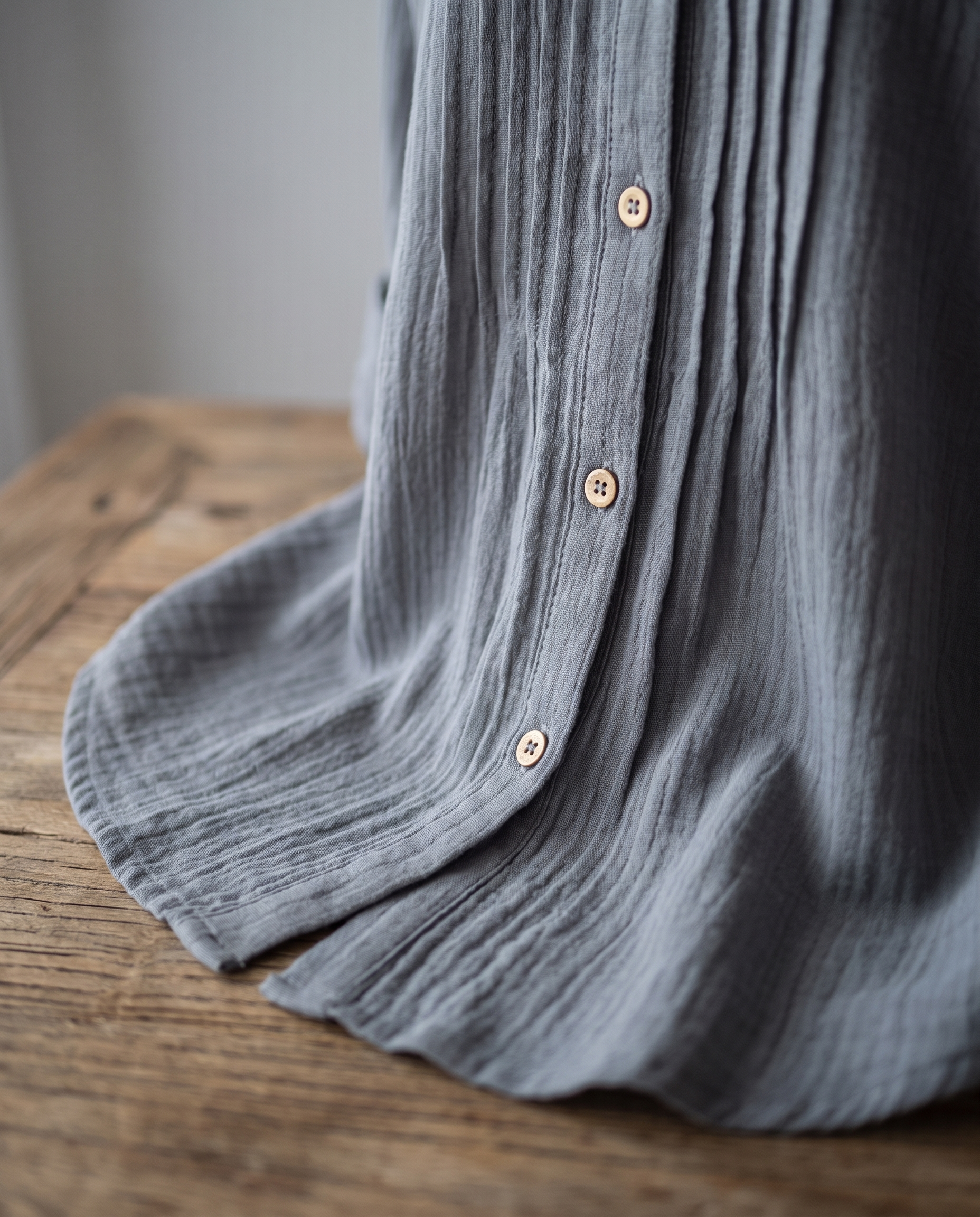 Close-up of the Abigail grey pleated blouse fabric, front pleat and buttons