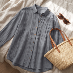 Flat-lay of the Abigail grey pleated blouse styled with a straw bag and sunglasses